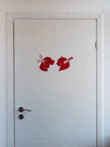 Intrarea de la salonul de cosmetica cu ilustratii sugestive pentru tuns